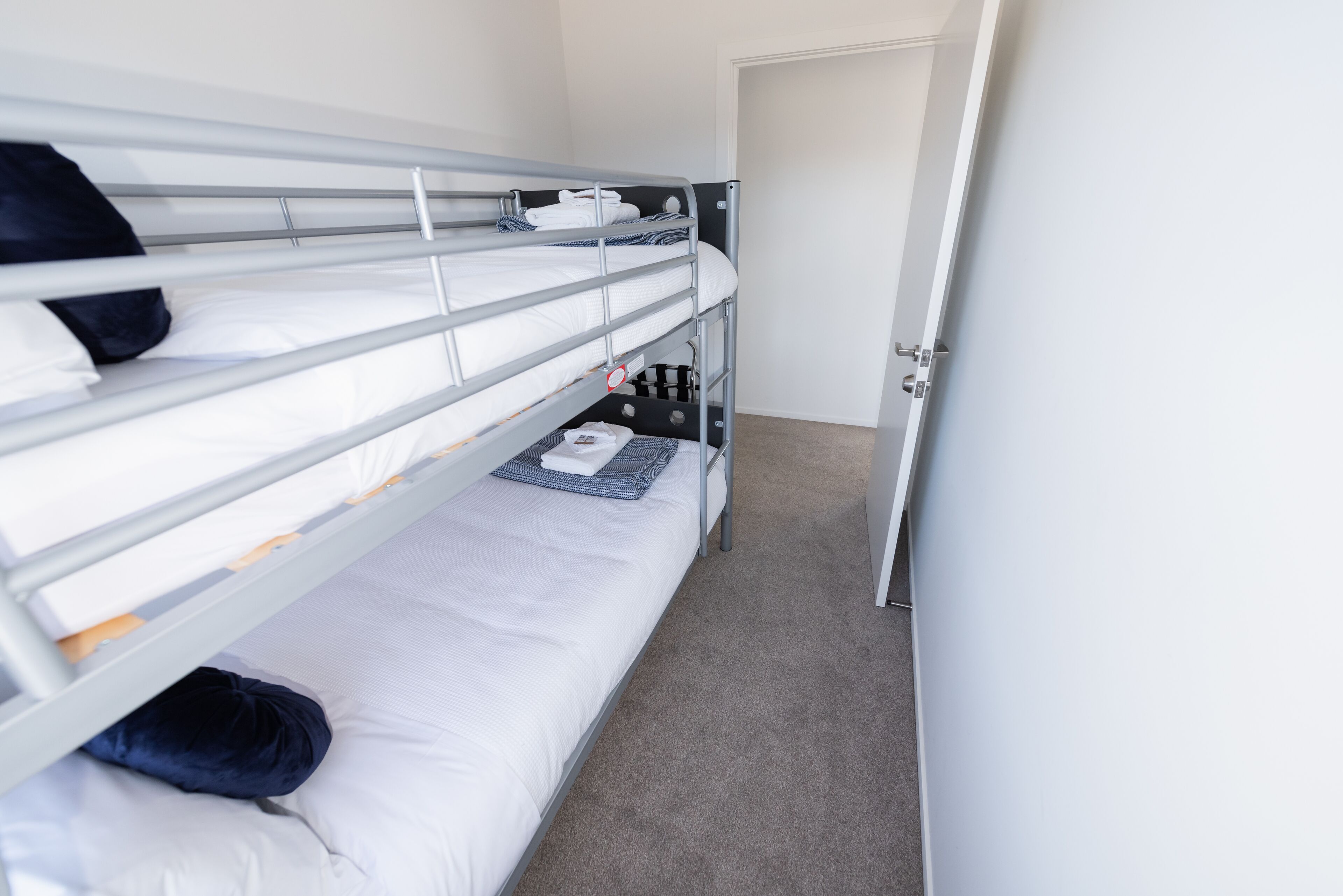 A bunk bed room with a door, a small table, and a carpeted floor.