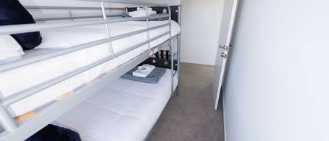 A bunk bed room with a door, a small table, and a carpeted floor.