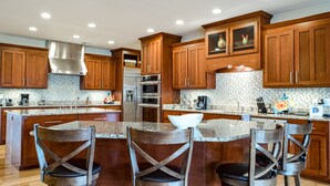 A modern kitchen with wooden cabinets, stainless steel appliances, and a central island with bar stools.