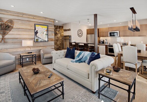 A modern living room with a sofa, coffee table, and a dining area with chairs.