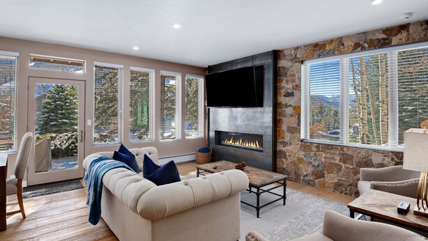 Una sala de estar moderna con chimenea, ventanas amplias y una pared decorativa de piedra.