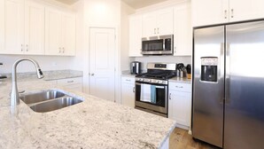 A modern kitchen with white cabinets, stainless steel appliances, and a granite countertop. - Waterpark Retreat w/ Lazy River, Pickleball Courts (Washington)