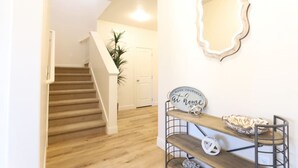 A staircase leading to a second floor, a wall-mounted mirror, and a shelf with decorative items. - Waterpark Retreat w/ Lazy River, Pickleball Courts (Washington)