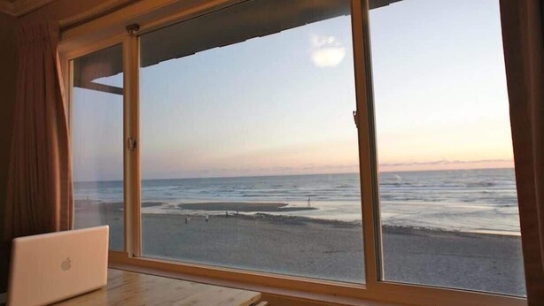 A room with a large window overlooking a beach. - Luxurious Oceanfront Suite - Sleeps 6 - Second Floor - Pool and Sauna! (Lincoln City)