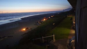 A beach view with a pathway leading to a building, a grassy area, and a railing along the beach. - Luxurious Oceanfront Suite - Sleeps 6 - Second Floor - Pool and Sauna! (Lincoln City)