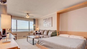 A hotel room with a large bed, a sofa, a desk, and a view of the ocean. - Luxurious Oceanfront Suite - Sleeps 6 - Second Floor - Pool and Sauna! (Lincoln City)