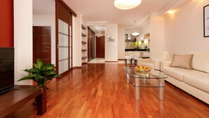 A modern living room with a glass coffee table, a sofa, and a TV. There is a wooden floor and a plant in the corner. - Modern Apartment in the Center | Balcony | Parking (Warszawa)