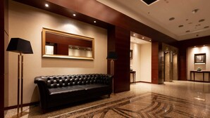 A lobby with a black leather sofa, a large mirror, and a polished marble floor. - Modern Apartment in the Center | Balcony | Parking (Warszawa)