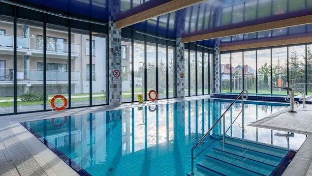An indoor swimming pool with clear glass walls, a tiled floor, and a lifebuoy.