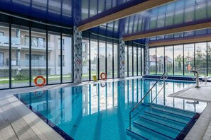 An indoor swimming pool with clear glass walls, a tiled floor, and a lifebuoy.