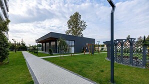 A modern building with a covered outdoor area, a paved walkway, and a playground.