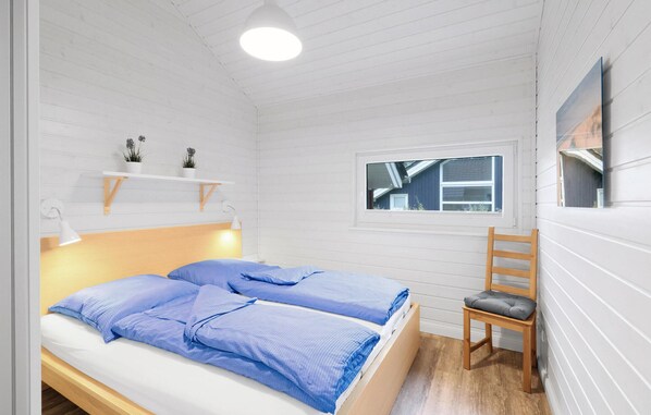 Een slaapkamer met twee bedden, een raam, een stoel en een plank met planten.