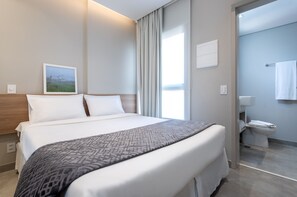 Een hotelkamer met een groot bed, een nachtkastje, een schilderij aan de muur en uitzicht op de badkamer.