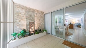 Ein modernes Interieur mit einer Steinwand, einer Glastür, die in einen Essbereich führt, und einer Pflanzengestaltung.