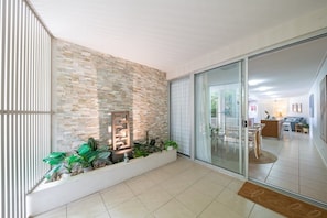A modern interior with a stone wall, a glass door leading to a dining area, and a plant arrangement. - Sun View On Seaview - Airlie Beach (Airlie Beach)
