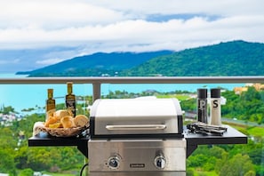 Una parrilla con condimentos y pan en un balcón con vistas a un paisaje pintoresco.