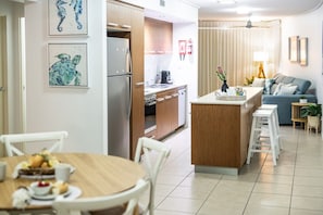 Una cocina moderna con armarios de madera, una isla central y un comedor con mesa y sillas redondas.