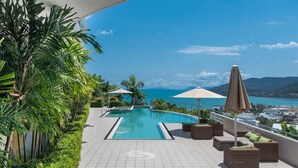 Ein Poolbereich auf dem Dach mit Blick auf das Meer, umgeben von Grünpflanzen und mit Gartenmöbeln ausgestattet.