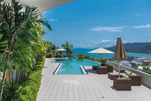 A rooftop pool area with a view of the sea, surrounded by greenery and furnished with outdoor seating. - Sun View On Seaview - Airlie Beach (Airlie Beach)