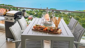 Ein Esstisch mit Meerblick, ein Grill und eine Flasche Champagner.