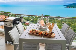 A dining table with a view of the sea, a grill, and a bottle of champagne. - Sun View On Seaview - Airlie Beach (Airlie Beach)