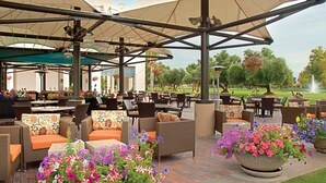 An outdoor patio area with wicker furniture, large umbrellas, and flower planters. - Club Wyndham Orange Tree Resort - 2 Bedroom (Scottsdale)