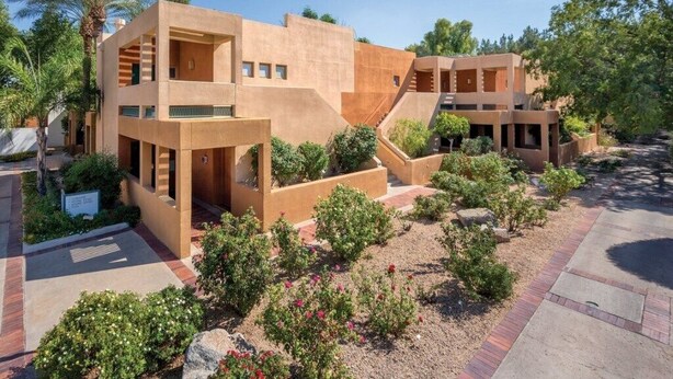 A modern building with multiple levels and balconies, surrounded by landscaped gardens and palm trees. - Club Wyndham Orange Tree Resort - 2 Bedroom (Scottsdale)