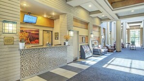 A hotel reception area with a tiled mosaic wall, a reception desk, a television screen, and a seating area with sofas and a coffee table. - Club Wyndham Orange Tree Resort - 2 Bedroom (Scottsdale)