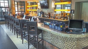 A bar area with a long counter, multiple bar stools, a television, and a variety of bottles and glasses. - Club Wyndham Orange Tree Resort - 2 Bedroom (Scottsdale)