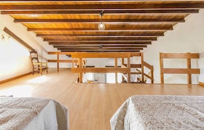 Relax in this spacious room with a high ceiling, featuring two beds and a central seating area.