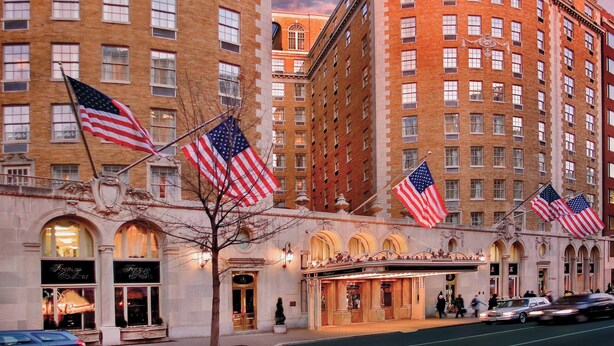 Un hôtel orné de plusieurs drapeaux américains, doté d’arcs en plein cintre au niveau des fenêtres et présentant un style architectural classique.