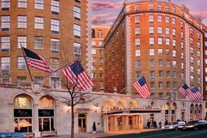 Un hotel con varias banderas estadounidenses, ventanas en arco y un estilo arquitectónico clásico.