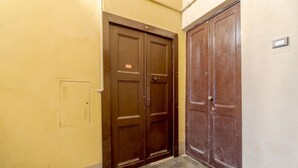 Ein Flur mit zwei Holztüren, einem Lichtschalter und einer kleinen Steckdose an der Wand.