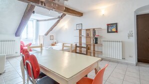 Ein Essbereich mit Holztisch und Stühlen, einem Heizkörper und einem Bücherregal.
