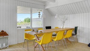 A dining area with a wooden table and yellow chairs, a white ceiling, and a view through large windows. - 3 bedroom lovely home in Slagelse (Slagelse)