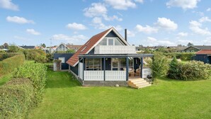 A single-story house with a sloped roof, a porch with white railings, and a small deck. - 3 bedroom lovely home in Slagelse (Slagelse)