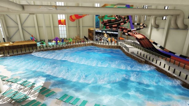 Parque acuático interior con piscina de olas, toboganes y sillas reclinables.