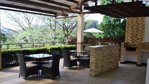Un patio al aire libre con una barra de piedra y sillas de mimbre.
