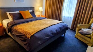 A hotel room with a large bed, two bedside tables with lamps, a chair, and a window with curtains. - Cosy Mid-Century home, Central, Off Street Parking and Fur Baby Friendly (Newington)