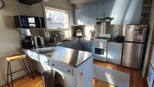 A modern kitchen with stainless steel appliances, a window, and a wooden floor. - Cosy Mid-Century home, Central, Off Street Parking and Fur Baby Friendly (Newington)