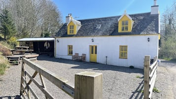 Standalone building with a pitched roof and chimney, situated on a gravel driveway.