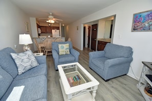 A living room with two sofas, a coffee table, and a dining area in the background. - Captain's Walk III 1D - Oceafront in Garden City Beach, SC (Garden City)