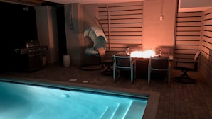 Un espace piscine comprenant un jacuzzi, un barbecue et une table avec des chaises.