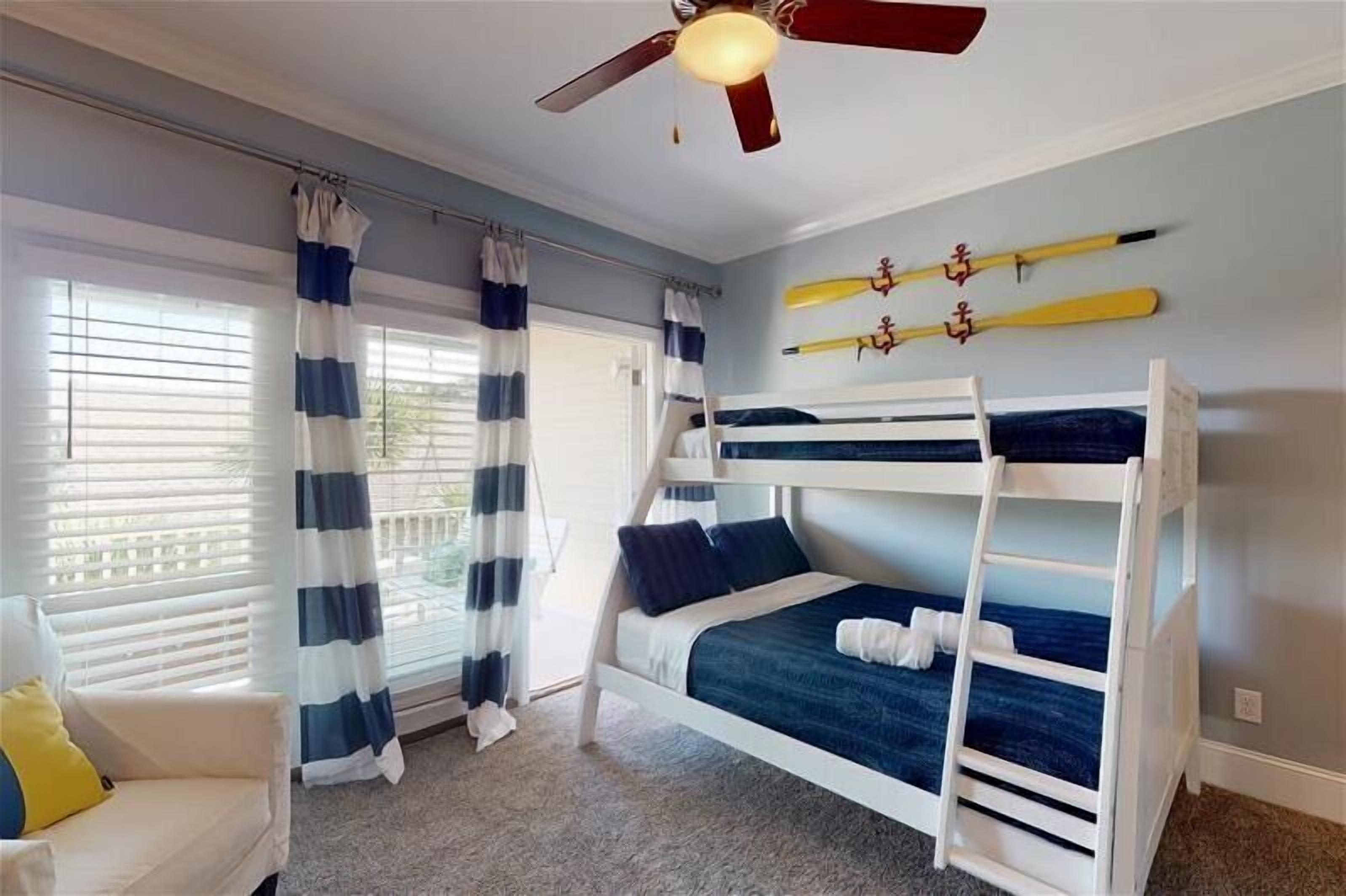A room with bunk beds, a ceiling fan, and curtains.