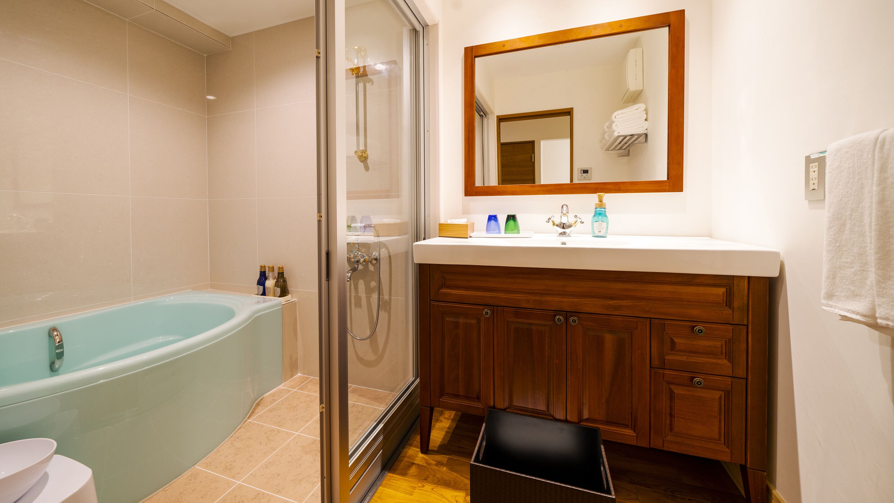 A bathroom with a bathtub, shower, vanity, and a mirror.