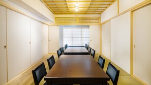A conference room with a long table, black chairs, and a wooden floor. - Umi No Terrace Yomitan Toya (Yomitan)
