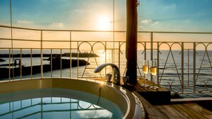 A sunlit outdoor area with a wooden deck, a hot tub, and a view of the sea. - Umi No Terrace Yomitan Toya (Yomitan)