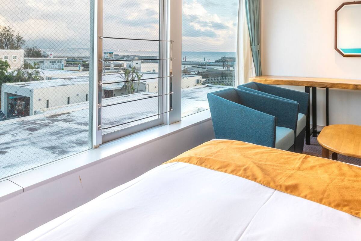 A hotel room with a bed, a desk, a chair, and a TV.