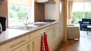 Cocina moderna con encimeras de granito, electrodomésticos de acero inoxidable y ventana con vistas a la vegetación.