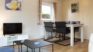 Una sala de estar moderna con un televisor de pantalla plana, una mesa de centro y un comedor con una mesa y sillas.